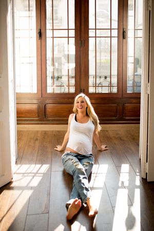 Cheerful pregnant woman relaxing on floor