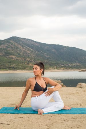 Woman practicing yoga outdoors near water
