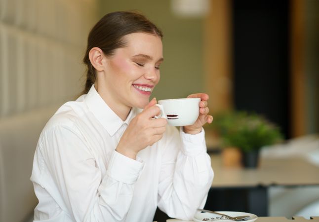 Woman laughing while drinking coffee in a cafeteria