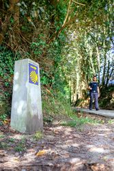 Milestone of Saint James way with pilgrim walking