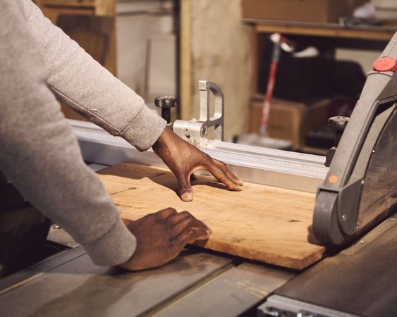 Black man cutting wood in studio