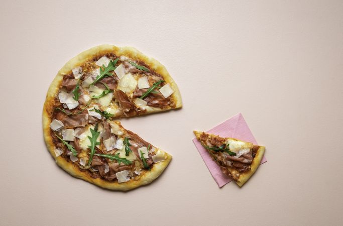 Prosciutto pizza with arugula and a single slice