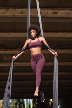 Slim woman doing yoga with aerial silks in city