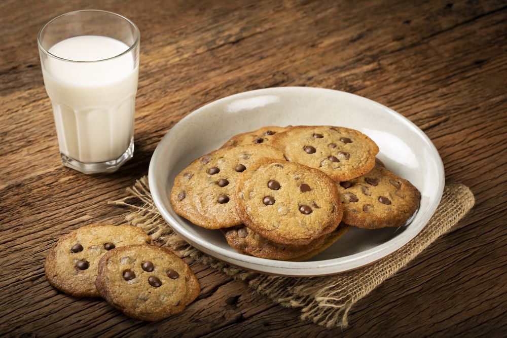 Delicious chocolate cookies with glass of milk on wooden table.