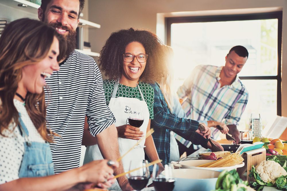 Multi-ethnic friends cooking pasta together in a bright kitchen