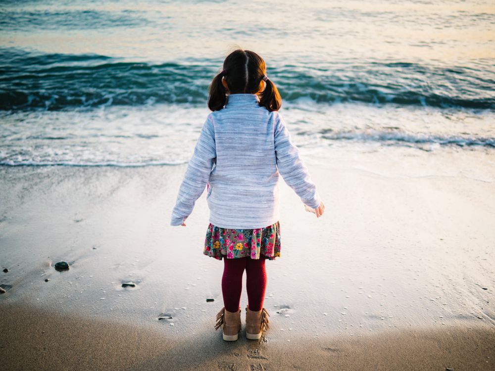 back view of little girl looking at sea