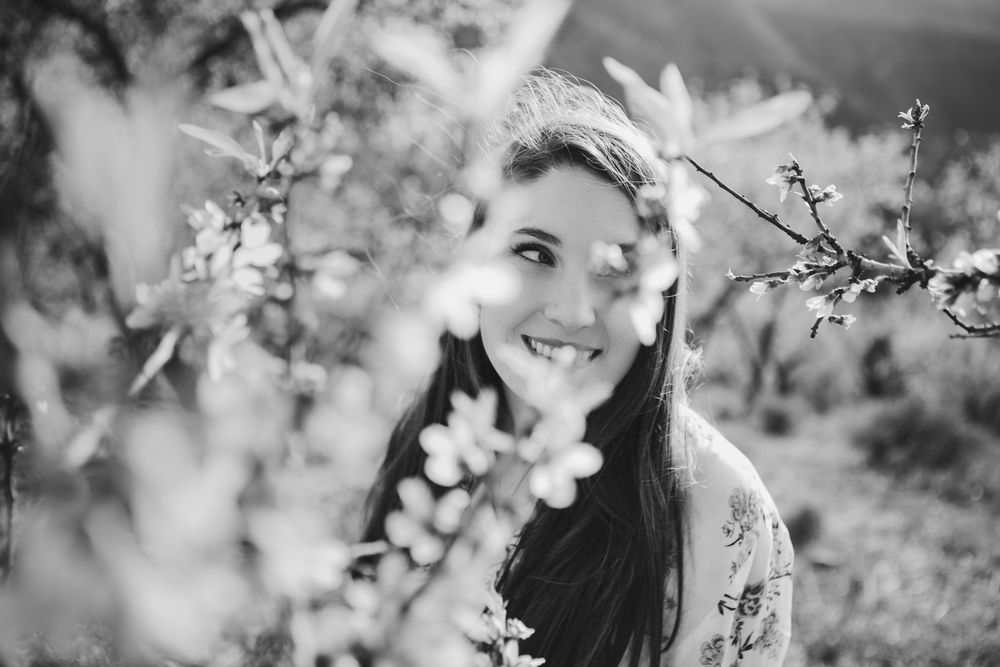 Young happy woman between trees in garden