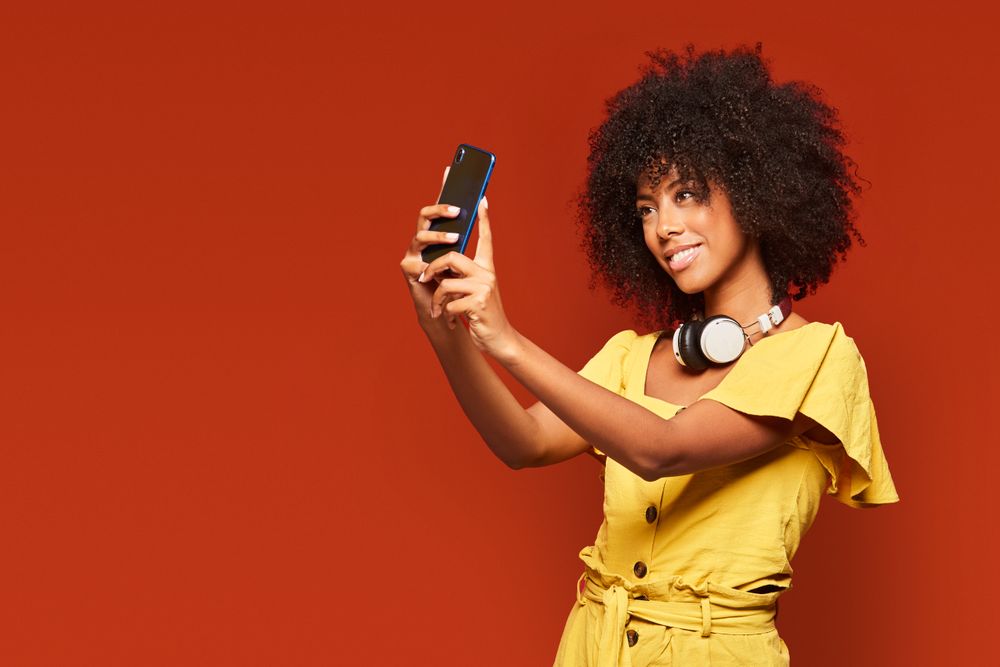 Trendy Black woman taking selfie with smartphone