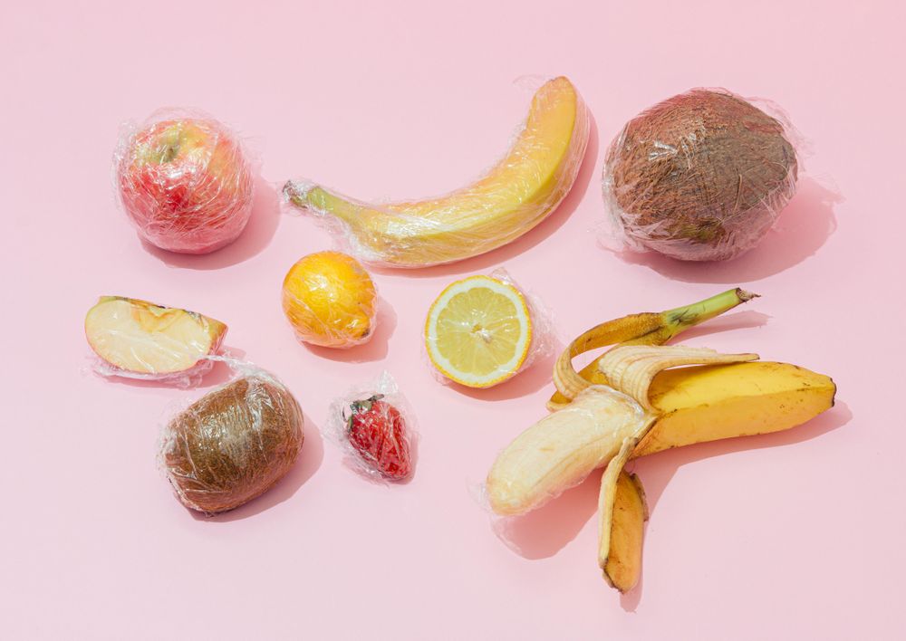 Plastic wrapped fruit on pink background