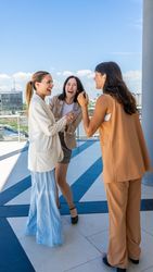 Three radiant women share a moment of joy, their laughter and smiles illuminaties the scene.
