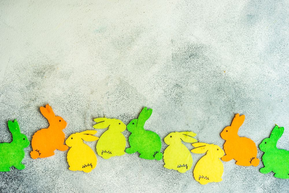 Easter holiday concept with colorful flat rabbit decorations on grey counter