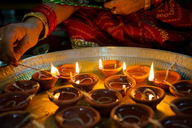 Cropped image of an older woman lighting up the diyas for Diwali festival