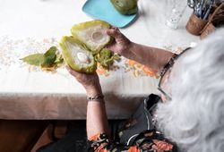 A woman is showing the inside of a fresh cooked chayote after peeling it