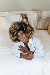 Smiling Black woman lying on bed in bedroom