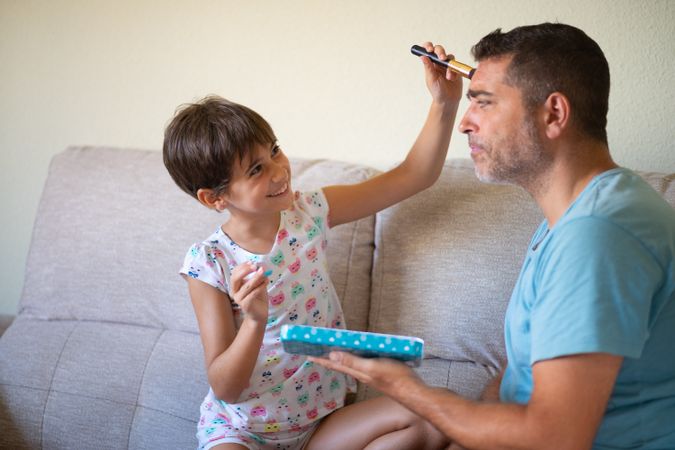 Little girl practicing make up on her dad