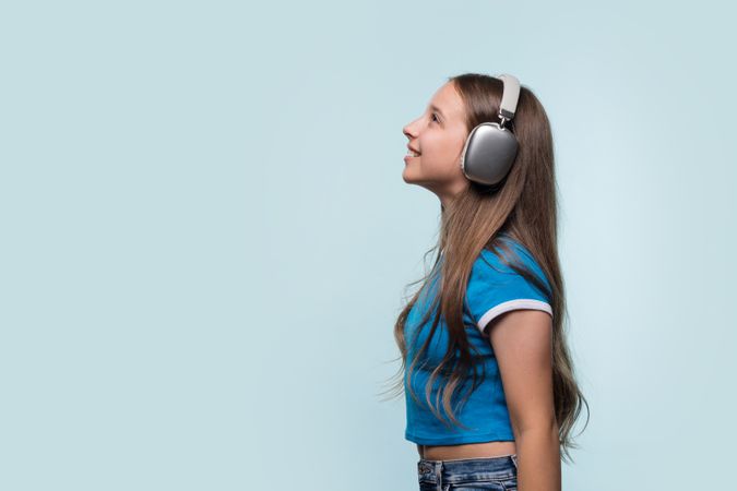 Young girl with headphones, listening to music and smiling.