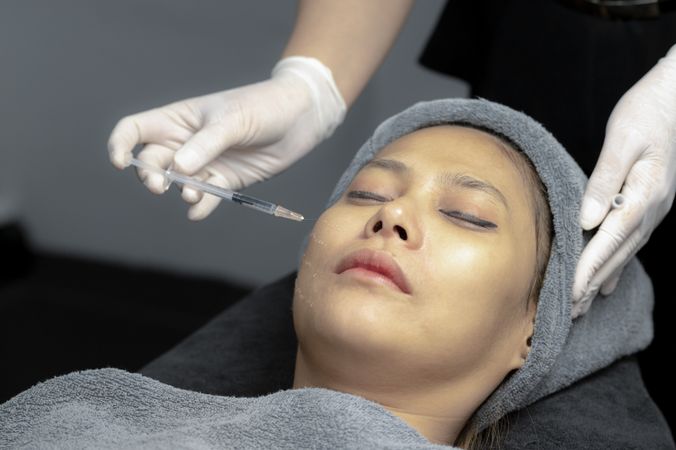 A young woman injects vitamins into her face in a beauty clinic.