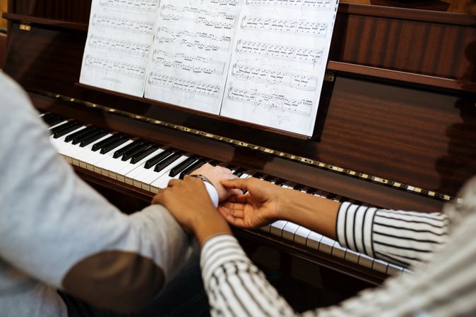 Man playing piano near woman teaching in studio