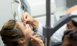 An ophthalmologist puts artificial tears in the person's eyes.