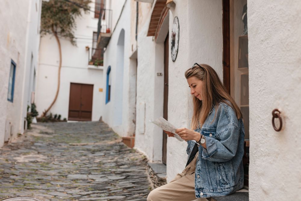 Side view of young woman sitting on window ledge with a paper map