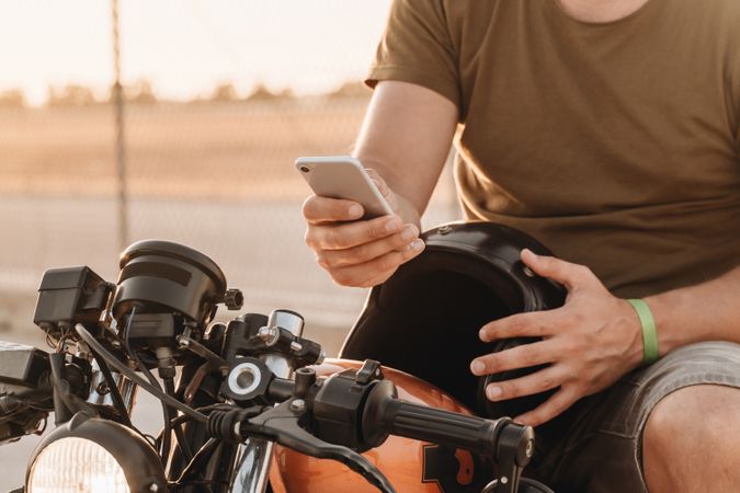 Man sitting on motorcycle and surfing mobile