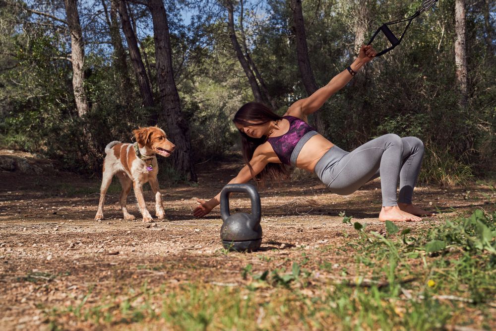 Woman exercising near dog in nature