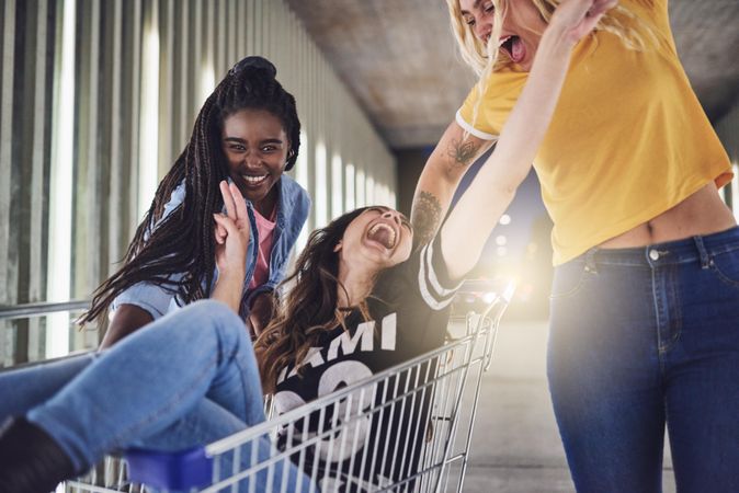 Silly group of young friends playing with shopping cart
