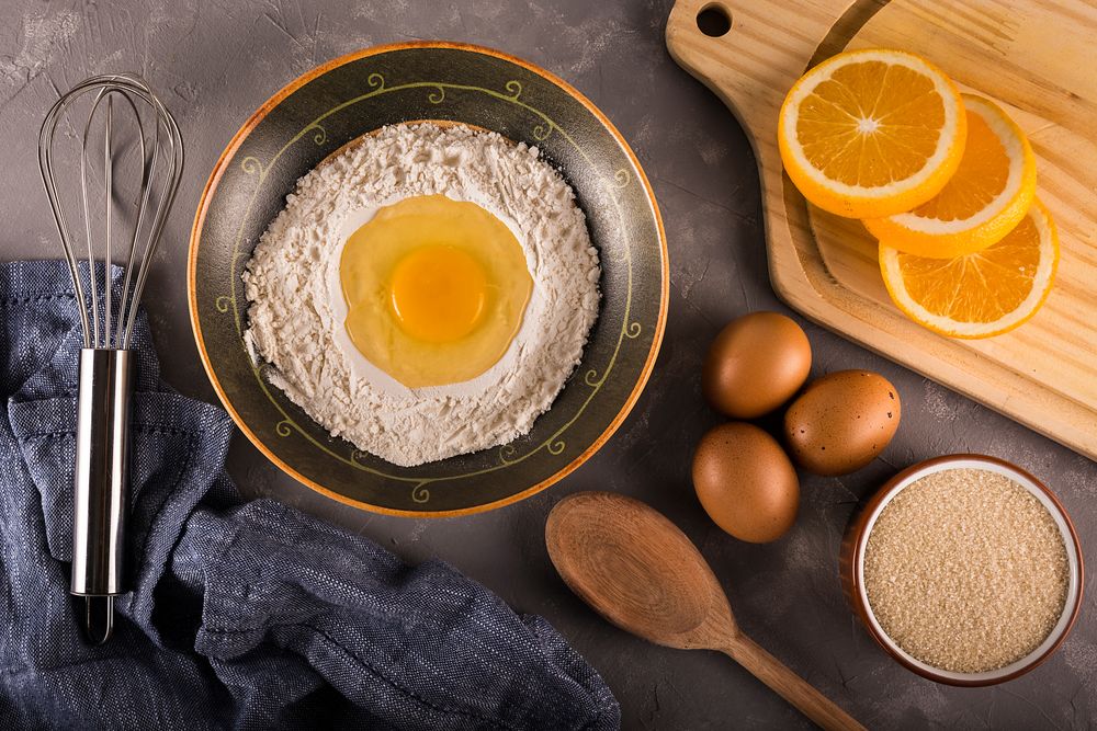 Top view of ingredients & utensils coming together to bake orange cake