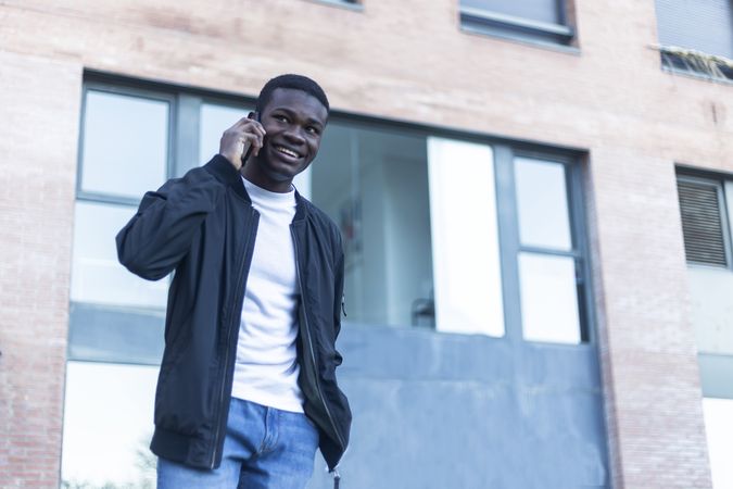 Smiling Black man walking outside talking on his phone