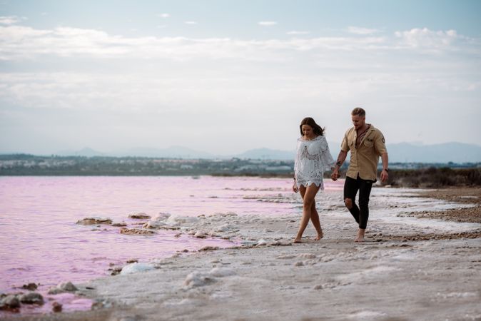 adorable couple walking on an amazing beach with pink water