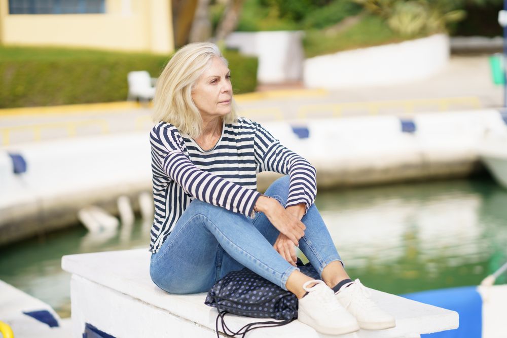 Older female relaxing on dock on sunny day