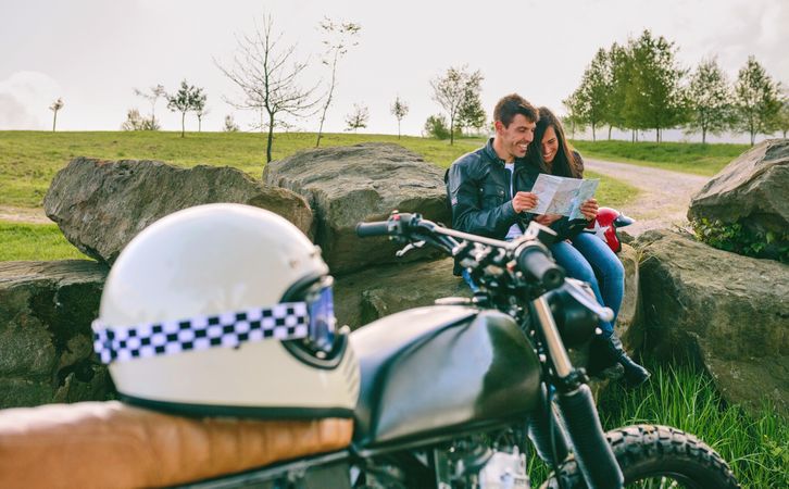 Couple sitting looking at a map with motorcycle