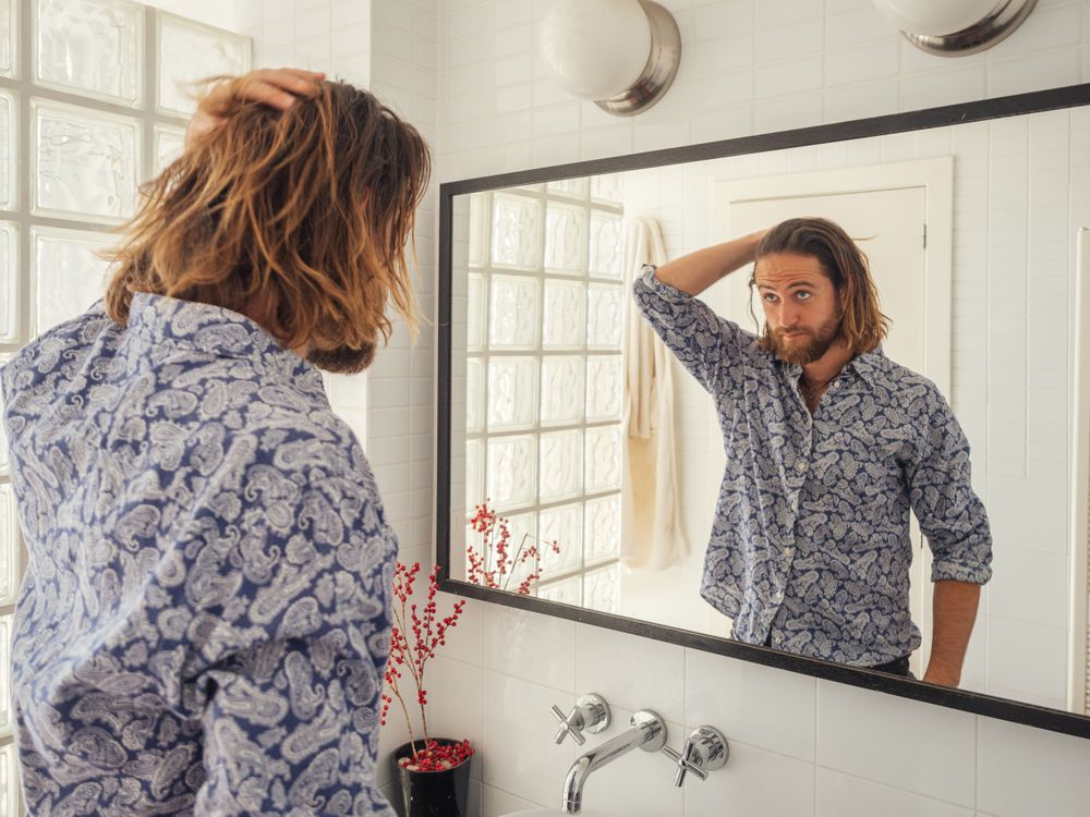 Handsome male checking hairstyle in mirror reflection