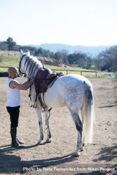 Handsome bald man leading his horse around a paddock 0yXq7a