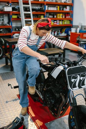 Mechanic woman starting custom motorcycle on factory