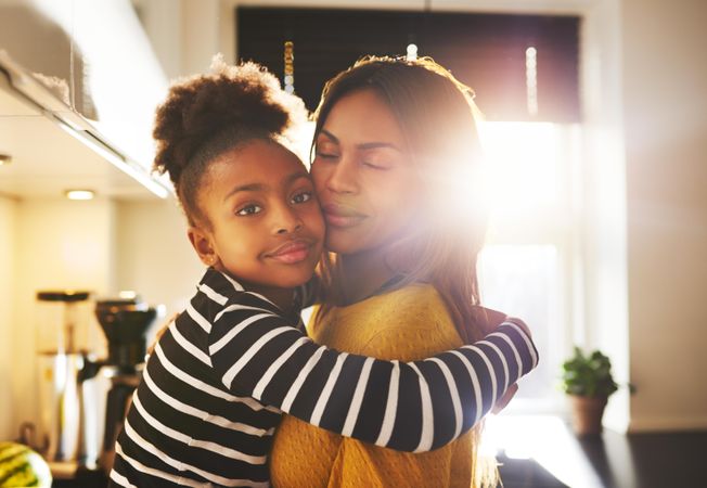 Mother and daughter hugging in bright kitchen