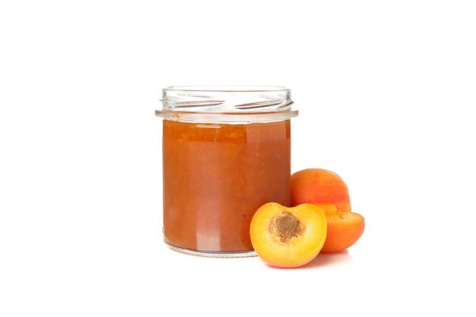 Glass jar with apricot jam isolated on blank background