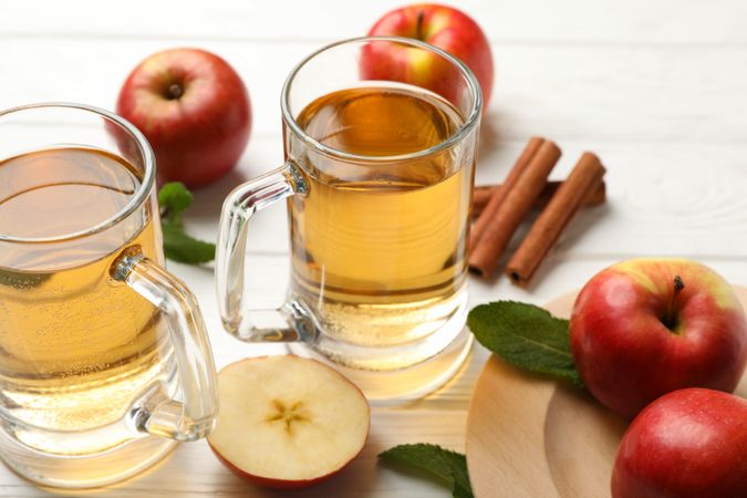 Composition with cider, cinnamon and apples on wooden background