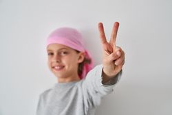 Cute child demonstrating V sign and smiling against white backgr