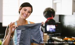Happy woman holding a shorts looking at camera recording content for her vlog on female sportswear 5oE9yb