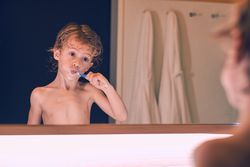Boy brushing teeth in bathroom of hotel room
