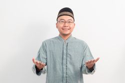 Asian Muslim man smiling doing greeting pose during Ramadan