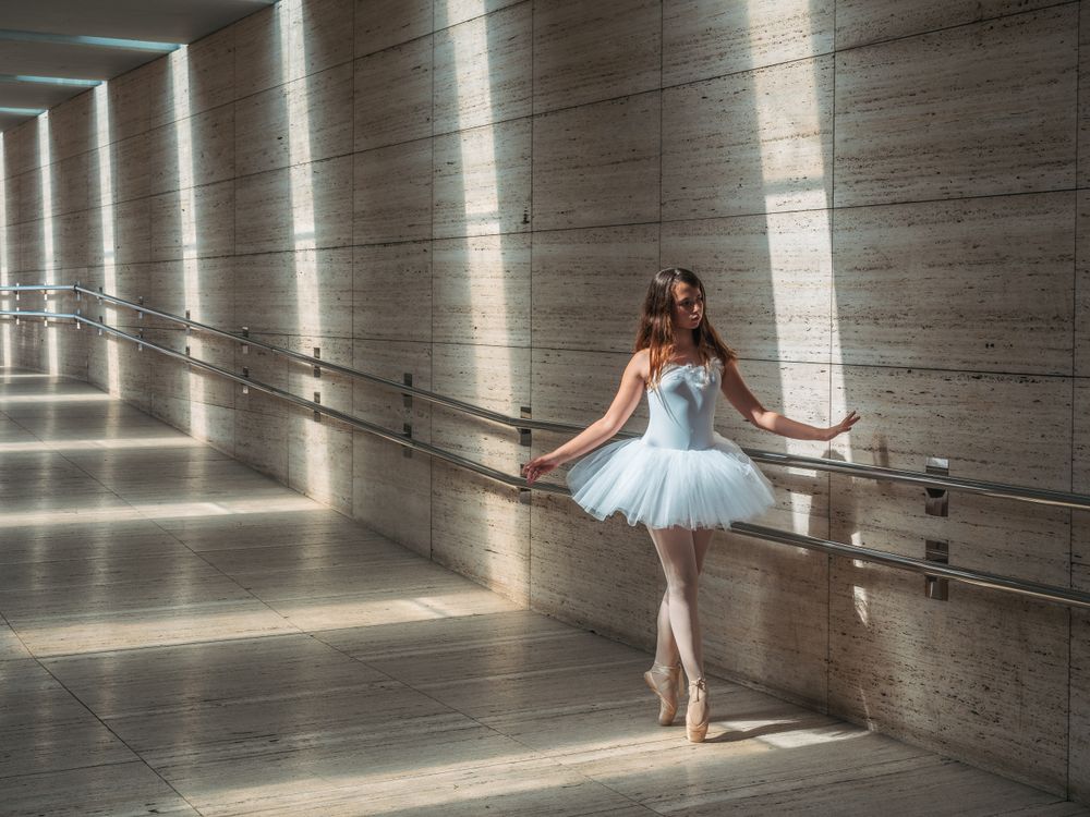 Ballerina doing ballet posing at rail in classroom