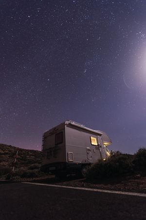 Caravan on roadside under night starry sky