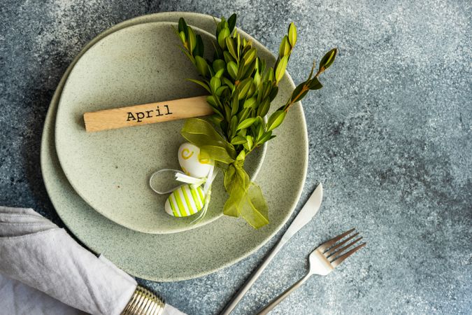 Easter concept with branch and green decorative eggs on ceramic plates with space for text