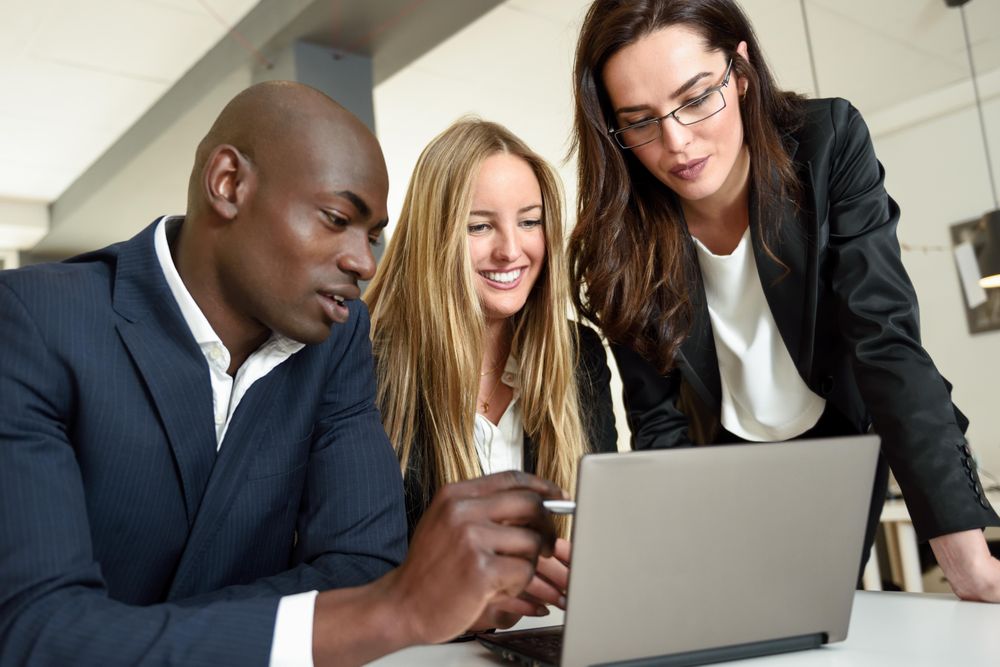 Multi-ethnic colleagues working together in office around a laptop