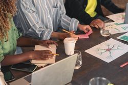 A group of professionals gather around a table, in a brainstorming session