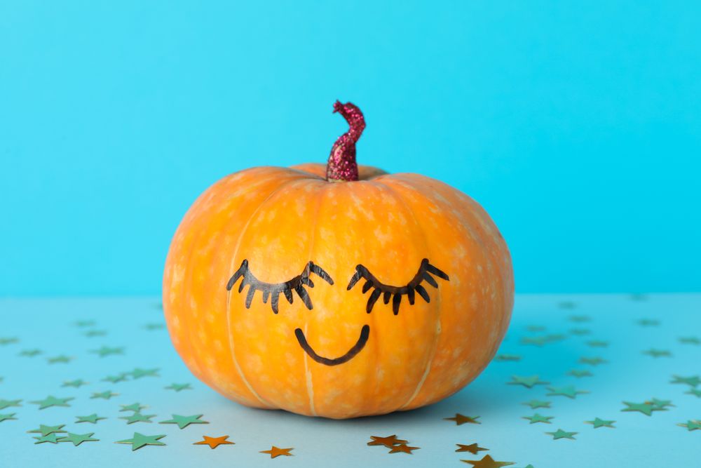 Pumpkin with smile on blue decorative background, space for text