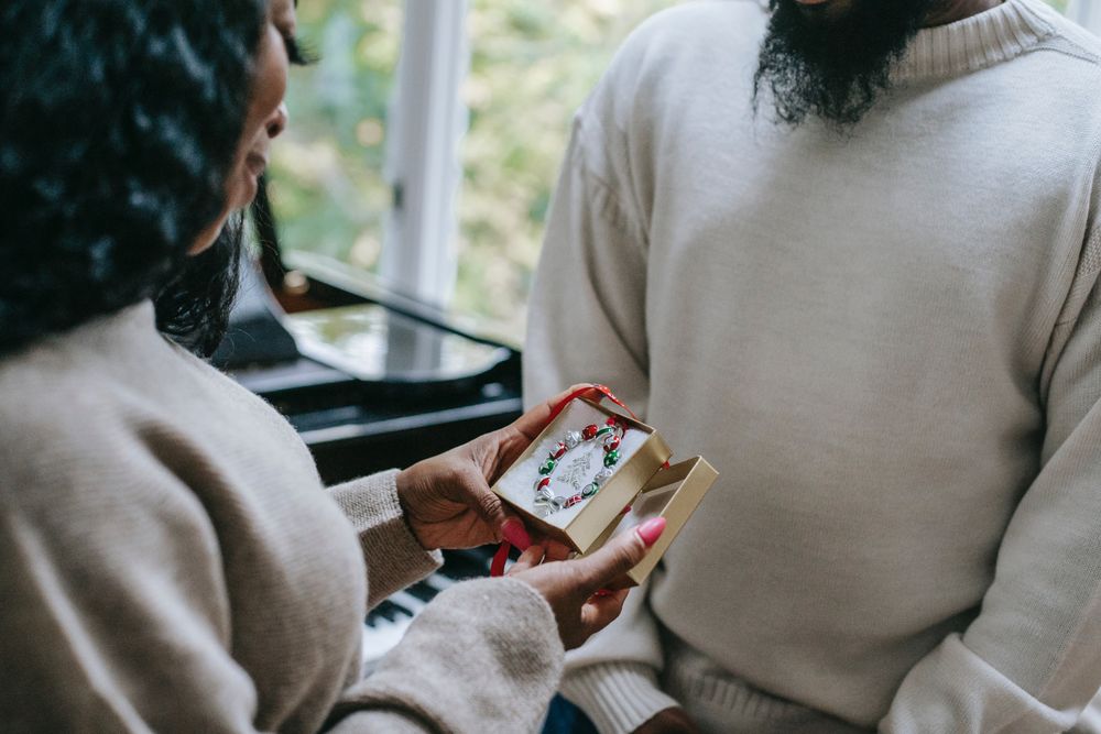 Woman opening a gift box from a man standing near