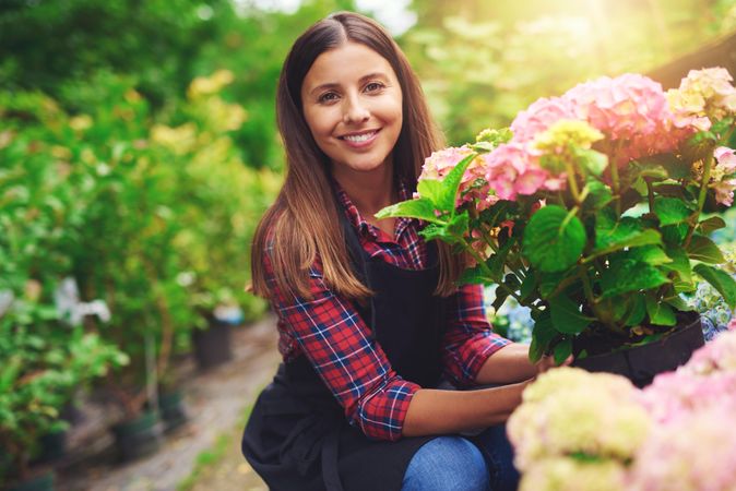 Smiling florist pictured with colorful flowers in a greenhouse